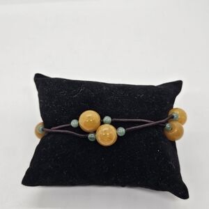 brown cord slider bracelet with green and yellow-orange stone beads